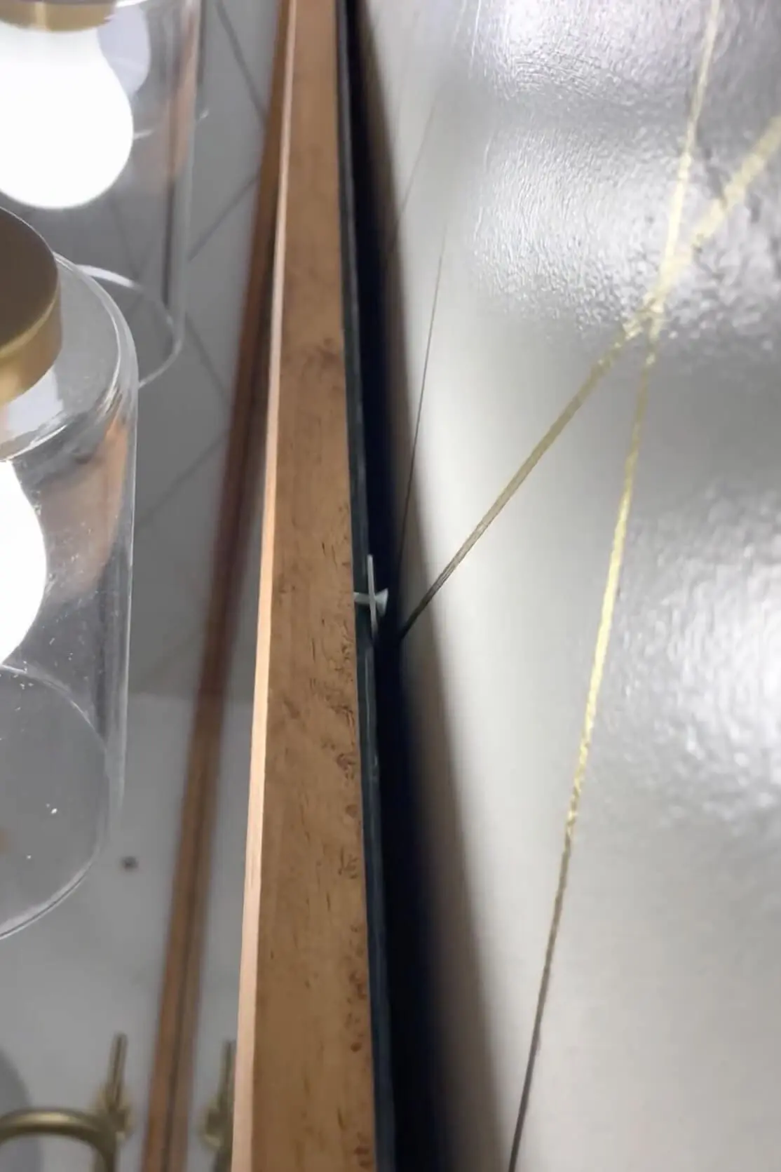 Attaching a frame to a bathroom mirror with a washer and screw.